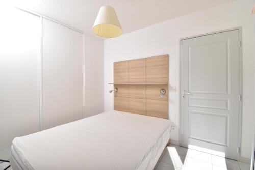 勒格罗-迪鲁瓦T2 Résidence Cap Camargue avec piscine的一间白色卧室,配有一张床和一个衣柜