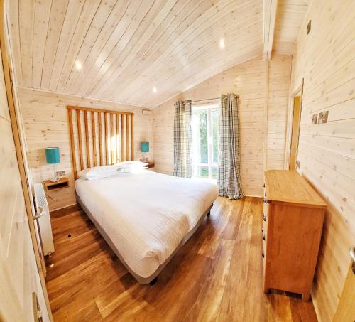 巴洛赫Skyline Lodge Loch Lomond Castle Lodges的一间卧室设有一张大床和木制天花板
