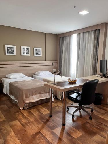 马瑙斯APART HOTEL SENSE II - Localizado em Hotel的一间卧室配有两张床、一张桌子和一台电视。
