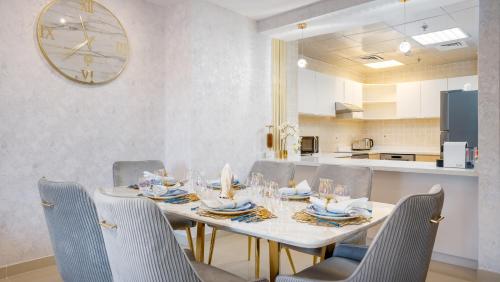 迪拜Exclusive Retreat GLOBALSTAY's New 3BR Townhouse with Private Pool的餐桌、椅子和墙上的时钟