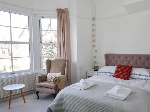 莫克姆112 Balmoral Road的卧室配有床、椅子和窗户。