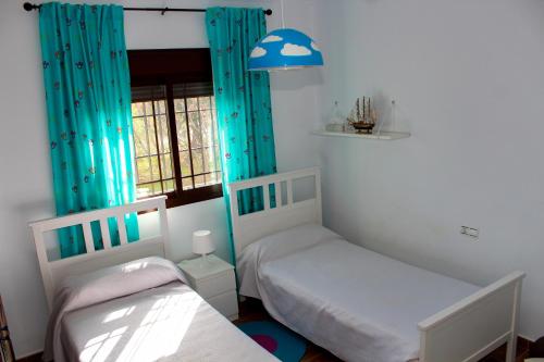 阿洛拉Casa Rural Caminito del Rey的配有蓝色窗帘的客房内的两张单人床