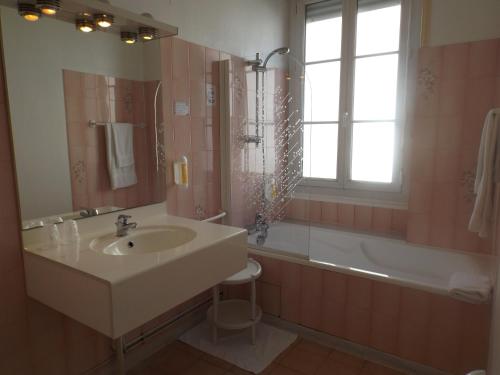 科涅克Logis Hôtel La Résidence的一间带水槽和浴缸的浴室以及窗户。