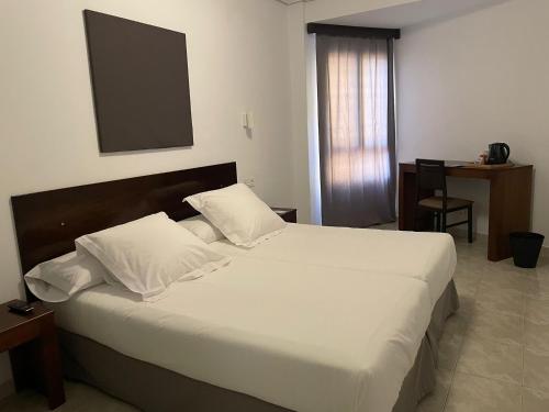 洛斯·亚诺斯·德·阿里丹维莱阿里达内酒店的卧室配有一张带白色床单和枕头的大床。