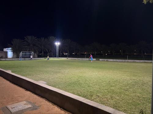 Al WāşilAl Khamail Land for Greenhostel的夜间场,人们玩足球