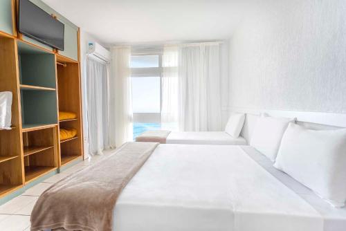 拉古纳Samba Laguna Tourist Hotel的白色的卧室设有一张大床和一个窗户