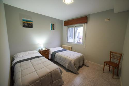 A MedorraHostal Molgas的一间卧室设有两张床、一把椅子和一个窗户。
