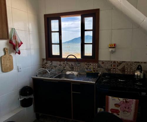 帕罗卡Recanto Pé na Areia SC的带水槽的厨房和海景窗户。