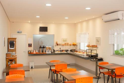伊图Hotel e Pousada Bem Bom - Itu的一间厨房,里面配有橙色的椅子和桌子