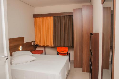 伊图Hotel e Pousada Bem Bom - Itu的卧室配有白色的床和橙色椅子