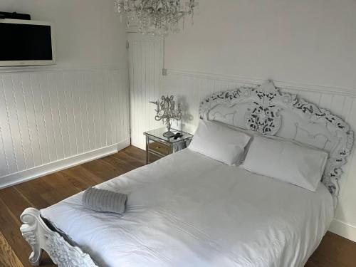 阿施Beautiful Little Bungalow, Indoor Fireplace, & Bar的卧室配有白色的床和墙上的电视。