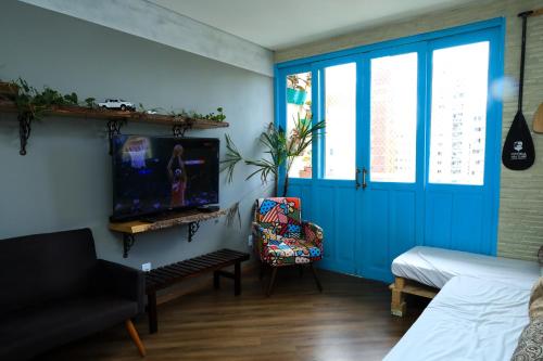 维多利亚Maravilhoso AP 3 Quartos Familiar - Wi fi- Praia do Canto的客厅设有蓝色门和电视。