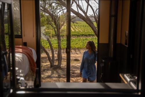赛特菲尔德CABN Off Grid Cabins Barossa的站在门外的小女孩,看着葡萄园