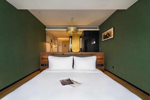 台州台州远洲逸廷酒店的一间卧室设有一张白色大床和绿色的墙壁