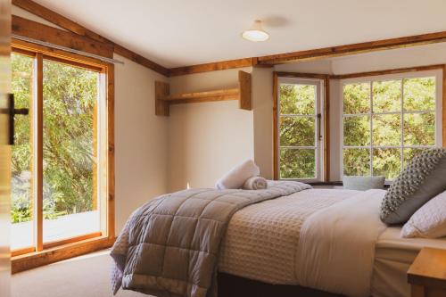 但尼丁Kaimata Cozy的一间卧室设有一张床和两个窗户。