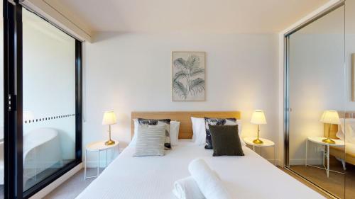 墨尔本Luxe Living的一间卧室配有一张带两盏灯的大型白色床。
