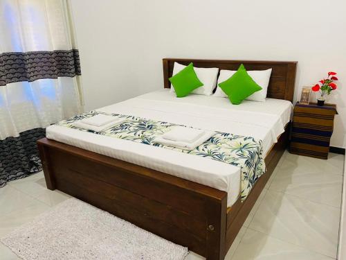 雅拉Udara Guest - Yala Safari的一间卧室配有一张带绿色枕头的大床