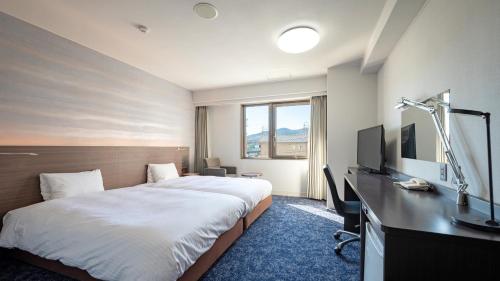 伊势市EN HOTEL Ise的酒店客房配有一张床、一张书桌和一台电视。