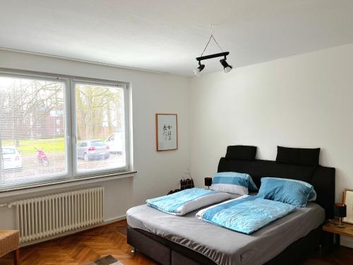 奥斯特霍尔茨-沙姆贝克Modern-Vintage Apartment的一间卧室配有一张带蓝色枕头的床和一扇窗户。