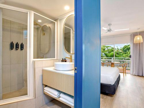凯恩斯Mercure Cairns的一间带水槽和淋浴的浴室以及一张床