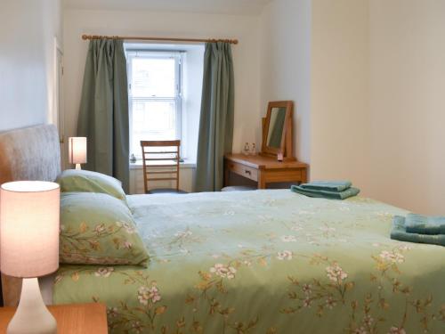 阿伯劳尔Rinnes Cottage的一间卧室配有一张带绿毯的床和窗户。