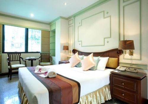 曼谷大华套房酒店的酒店客房设有一张大床和一张书桌。