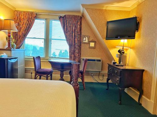 温斯洛普Winthrop Arms Hotel Restaurant Logan Airport的酒店客房设有床、桌子和电视。