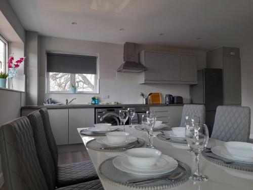 CranfordApartments Heathrow - Hounslow的厨房配有带盘子和酒杯的桌子