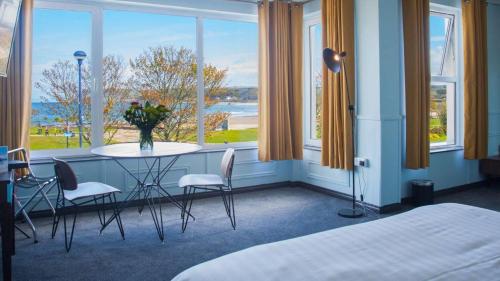 巴利卡斯尔Marine Hotel Ballycastle的客房设有桌椅和窗户。