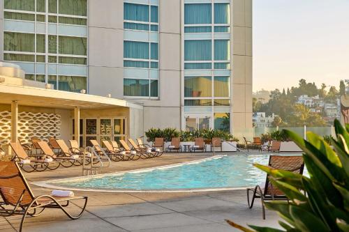 洛杉矶洛伊斯好莱坞酒店的酒店游泳池设有椅子,酒店大楼