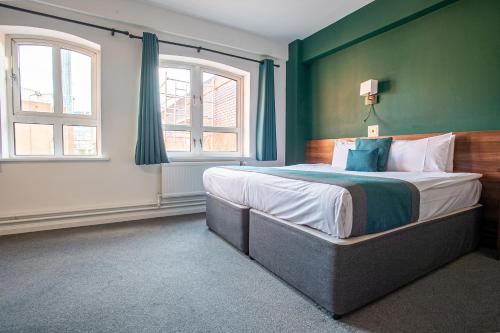 曼彻斯特城堡原野酒店的一间卧室设有一张大床,拥有绿色的墙壁和窗户。