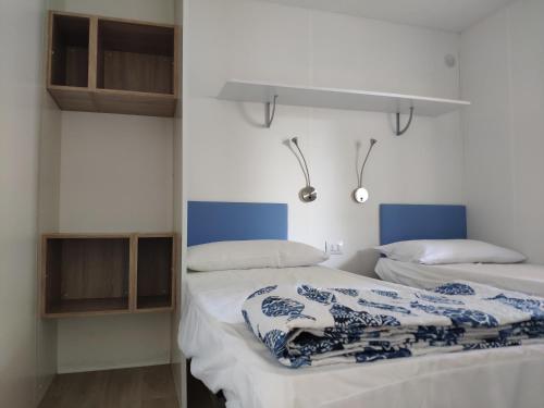 伊塞奥Camping Sassabanek的配有白色墙壁和蓝色色调的客房内的两张床