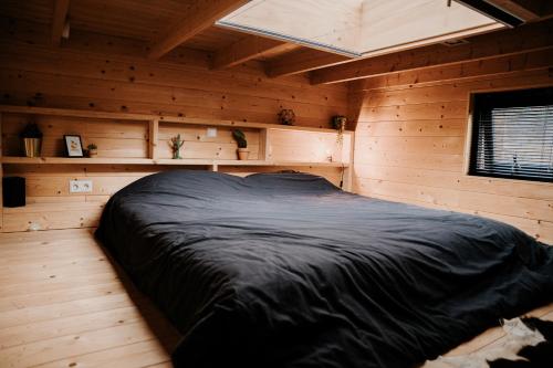 贝克贝亨Tiny house op de Veluwe的木制客房内的一张黑色床