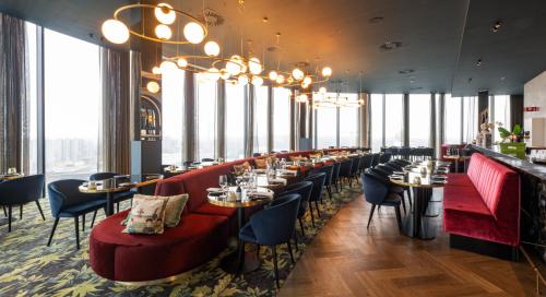 根特Van der Valk Hotel Gent的餐厅设有桌椅和大窗户。