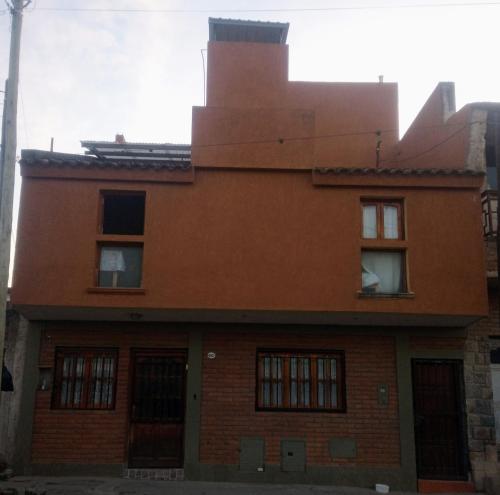 圣萨尔瓦多德朱Hostal Tía Dora的一座古老的橙色砖砌建筑,设有窗户