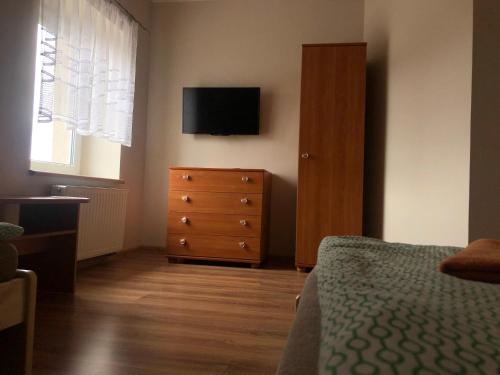 罗兹Piątka noclegi- Łódź的一间卧室配有一张床和一个带电视的梳妆台