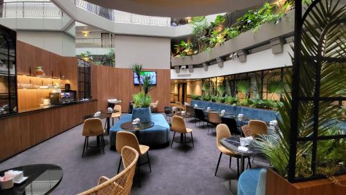 塞纳河畔讷伊巴黎讷伊酒店的一间设有桌椅的餐厅,种植了植物