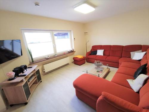 AllenbachFerienhaus Clarissa的客厅配有红色沙发和电视