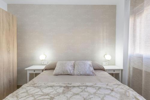 格拉纳达Neptuno Deluxe的一间卧室配有一张带两张桌子和两盏灯的床。