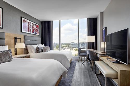 阿林顿Live! by Loews - Arlington, TX的酒店客房设有两张床、一张桌子和一台电视。