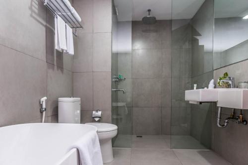 马卡萨KHAS Makassar Hotel的浴室配有卫生间、盥洗盆和淋浴。