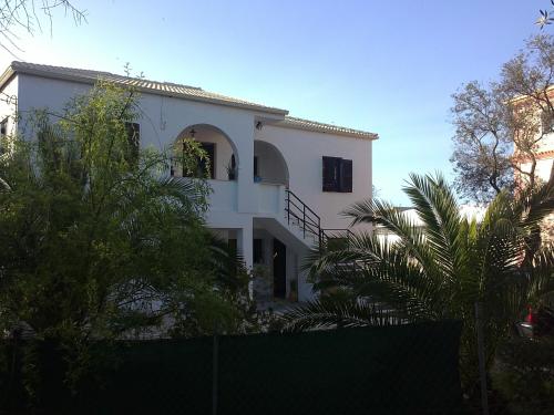 罗达Alexander Apartments的带阳台和棕榈树的白色房屋
