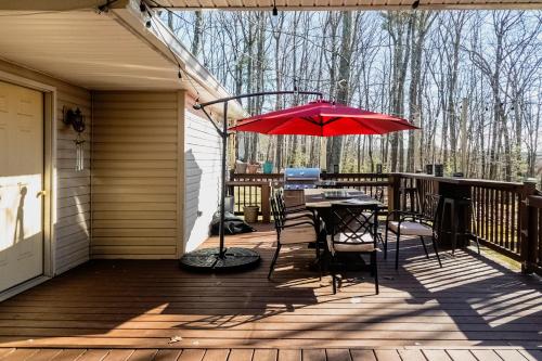 东斯特劳兹堡Blue Mountain Lake Pocono House的一个带桌子和红色遮阳伞的庭院