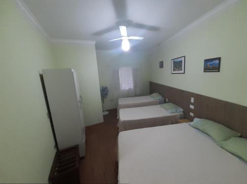 圣代佩德罗Apartamento São Pedro SP的客房设有三张床和吊扇。
