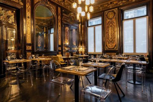 里尔Best Western Urban Hotel的一间设有桌椅的餐厅,位于带金色墙壁的房间