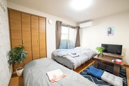 东京ミニマリズムホテル葛飾的一间卧室配有两张床、一张桌子和一台电视。