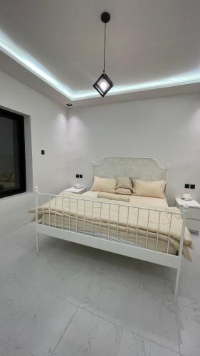 阿哈达بيت الجبل عوائل فقط的白色的客房内的一张白色的床,配有两张桌子