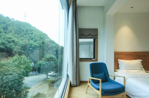 黄山风景区茶民宿（黄山景区免费接送）的一间卧室配有一张床、一把蓝椅和一个窗户。