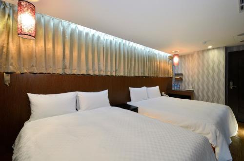 台北华大旅店-南西馆的配有白色床单的酒店客房内的两张床