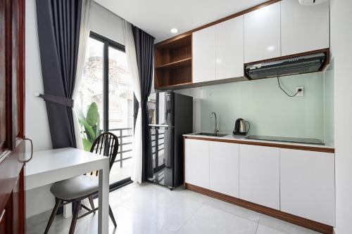 胡志明市Spring Hill Apartment -The High Class的厨房配有白色橱柜、桌子和窗户。